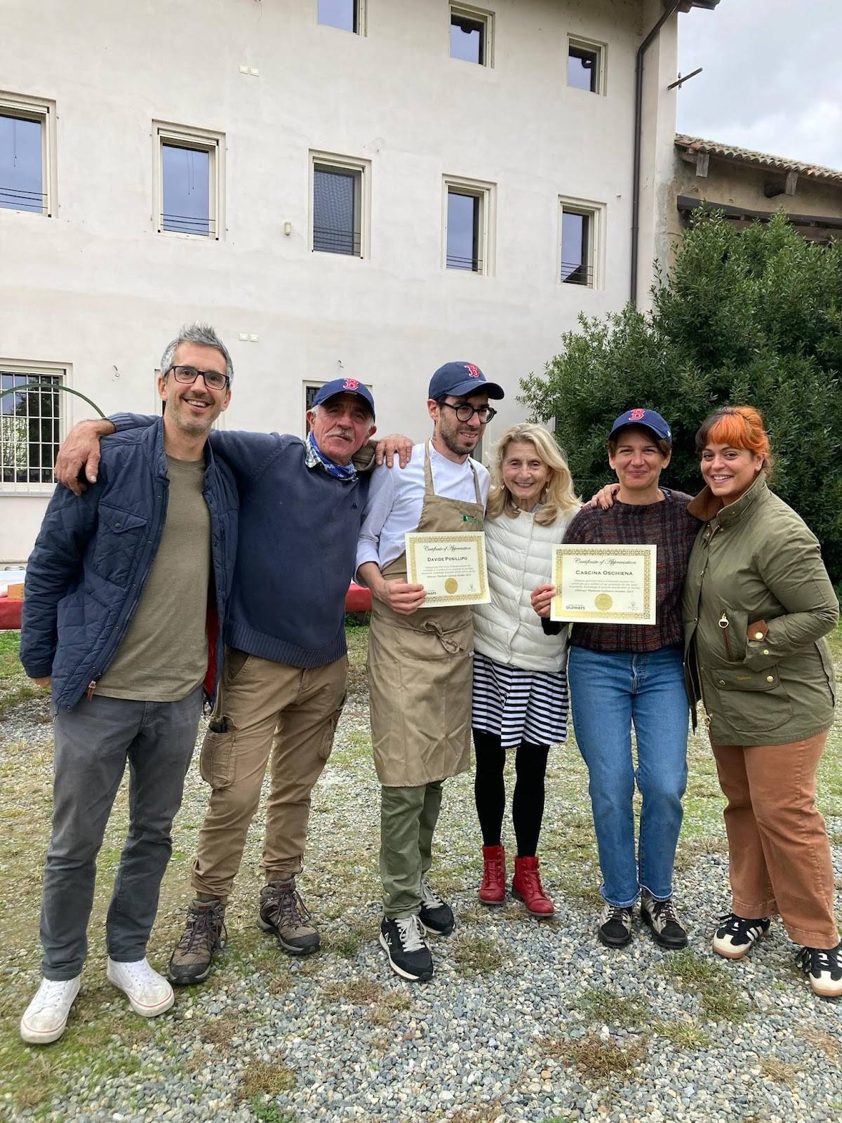 A group of individuals holding their certificates in celebration, positioned in front of a significant building.