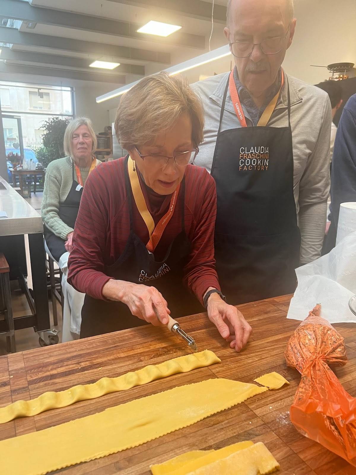 A team of people is actively preparing pasta in a kitchen, emphasizing collaboration and the joy of cooking together.