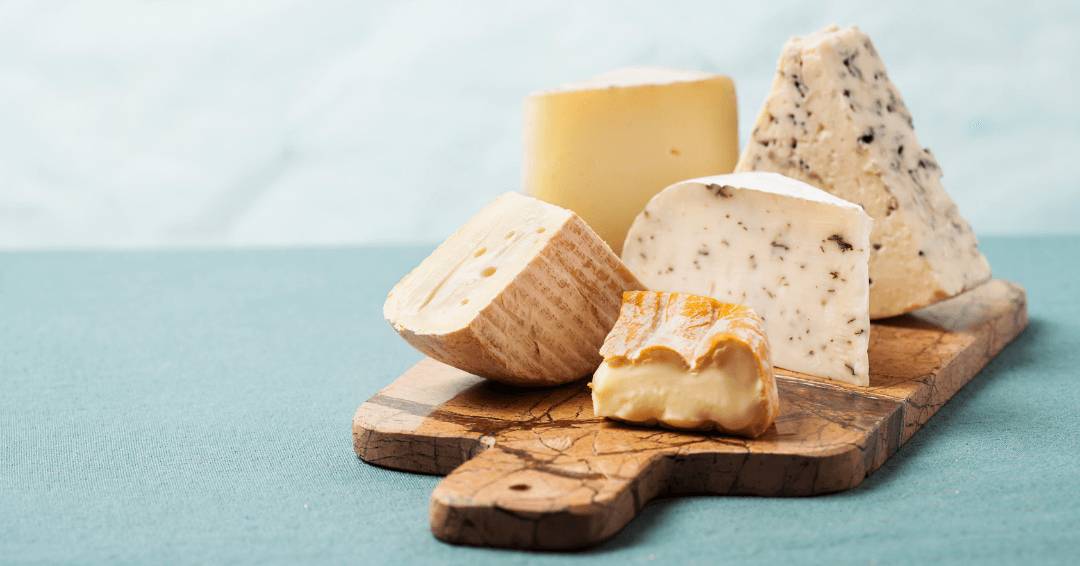 A beautifully arranged wooden board with various cheeses, emphasizing their distinct textures and appealing visual contrast.