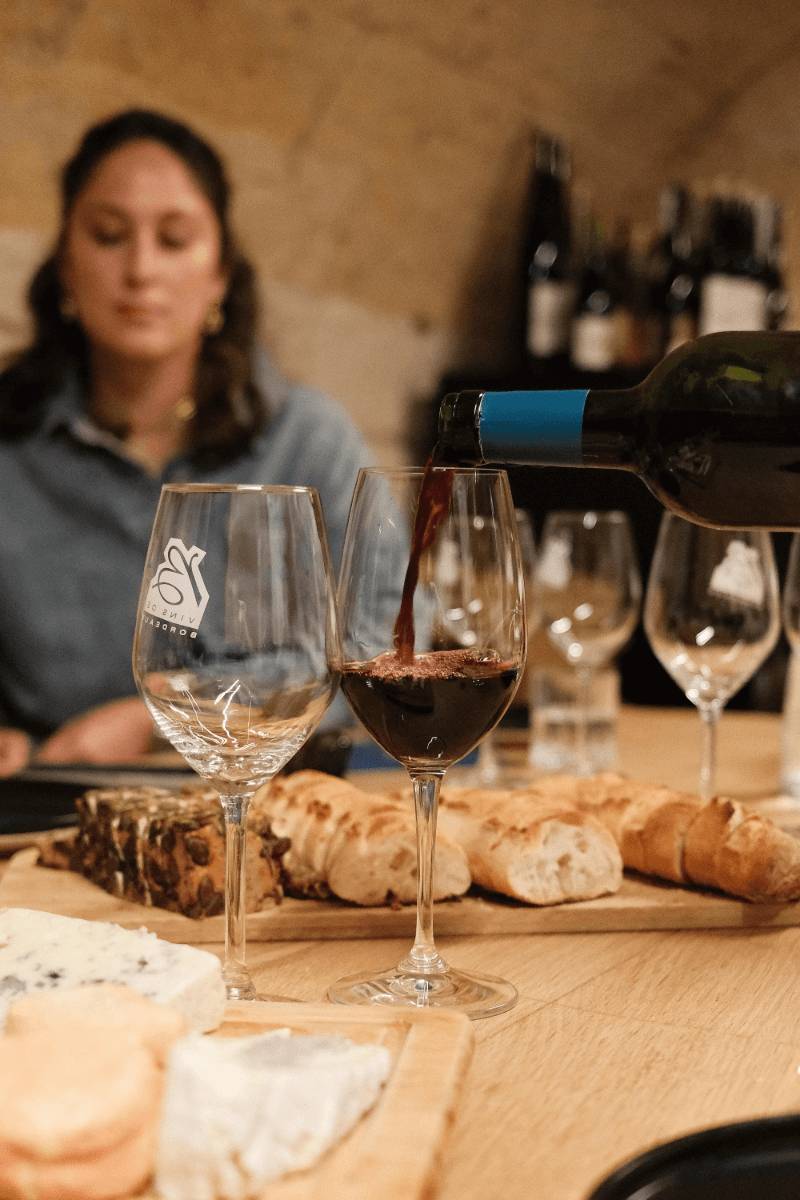 A woman is pouring a glass of wine from a bottle