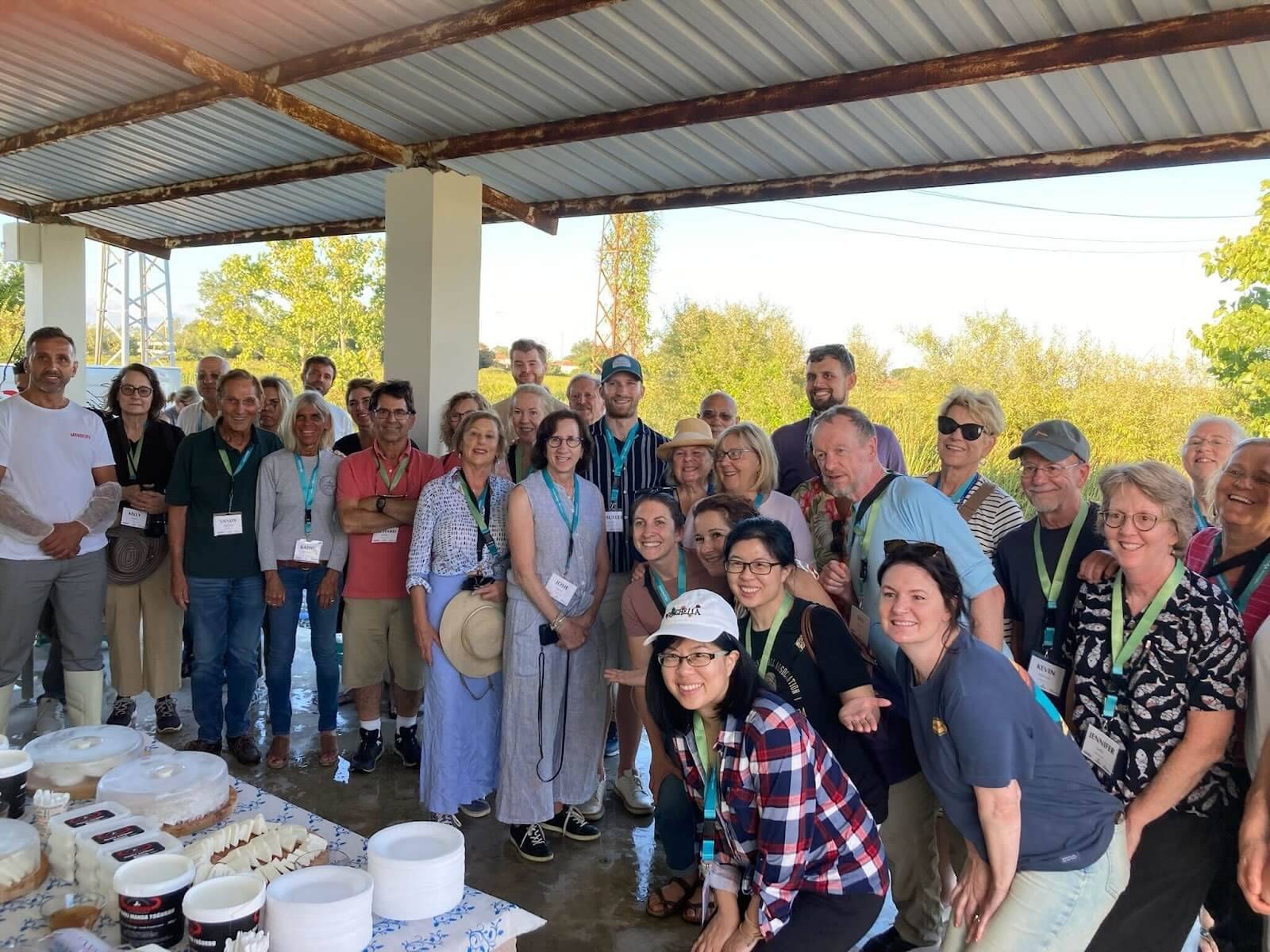 A group of people smiling and posing for a photo in front of a table filled with various dishes and drinks.