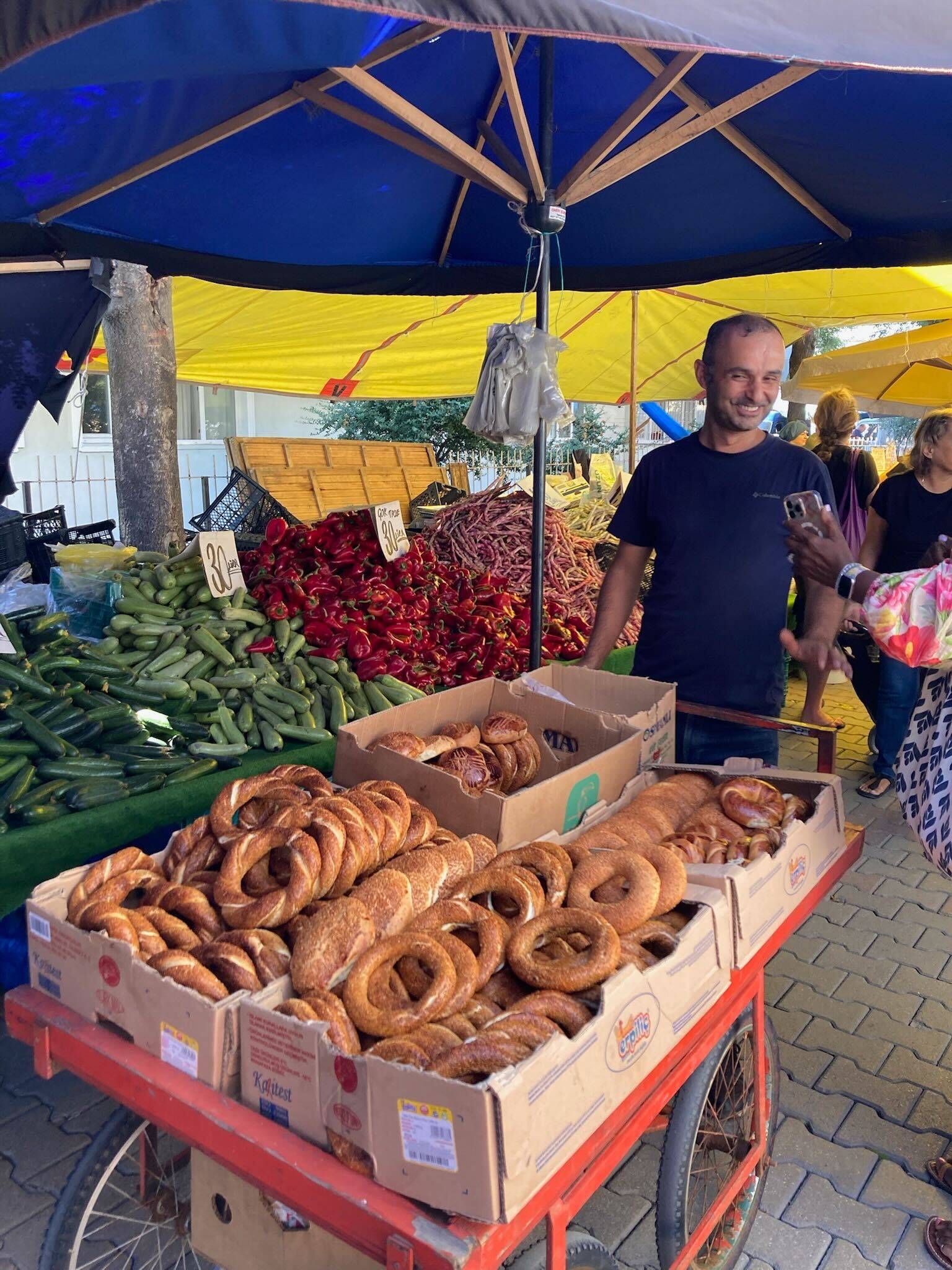 A woman holds a cart overflowing with various types of bread in a bright, well-lit bakery setting.