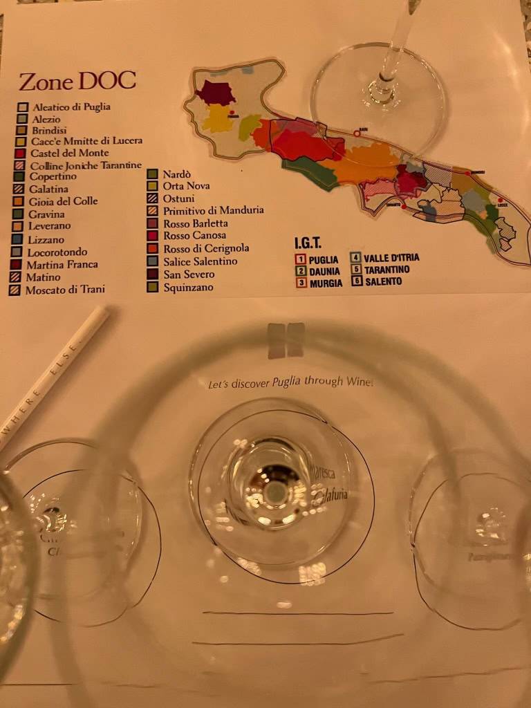 Wine tasting setup with map of Puglia wine regions and empty glasses.