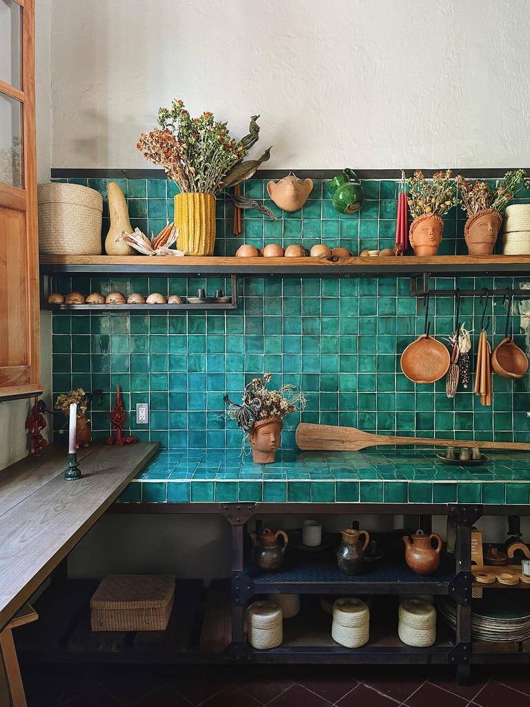 A kitchen featuring a green tile counter and matching shelves, creating a cohesive and vibrant design.