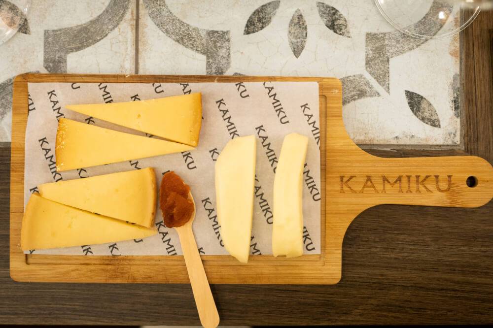 A wooden cutting board with different types of cheese
