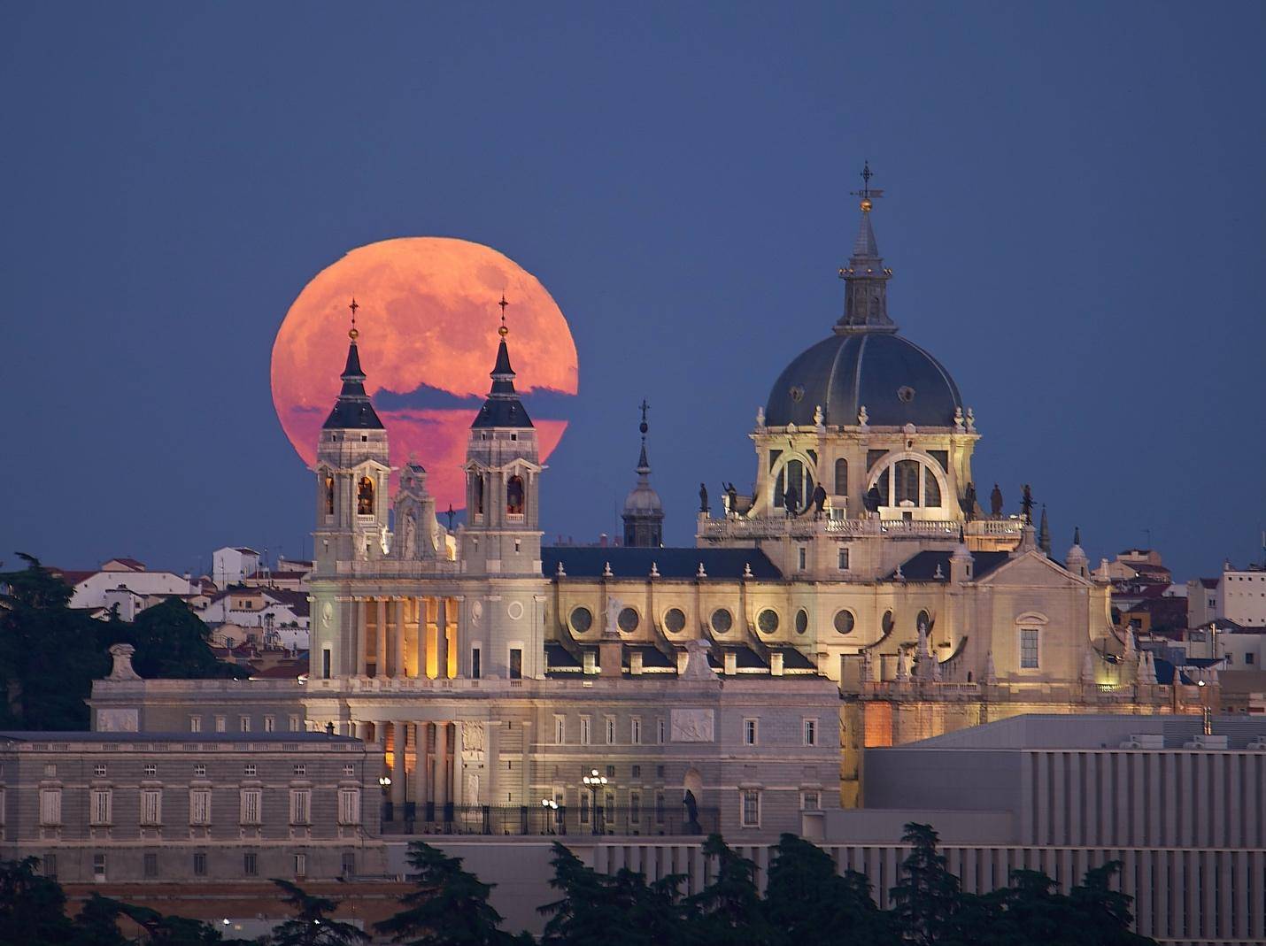 The moon rises over the skyline of Madrid