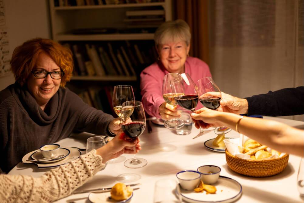 Three women raise their wine glasses in a toast
