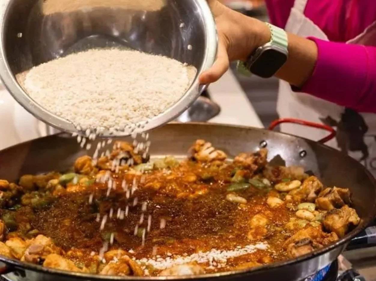 a woman add rice to a cooking pan
