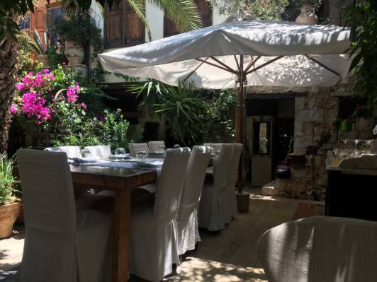 A table covered with white cloths, elegantly set for a formal dining occasion