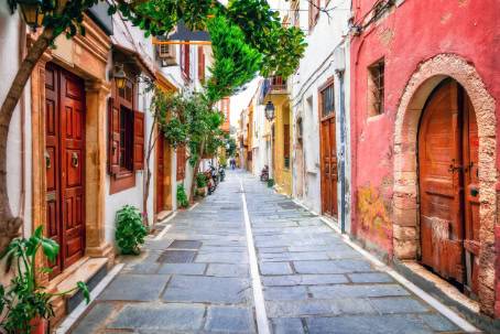 A narrow street lined with vibrant buildings featuring wooden doors in various colors.
