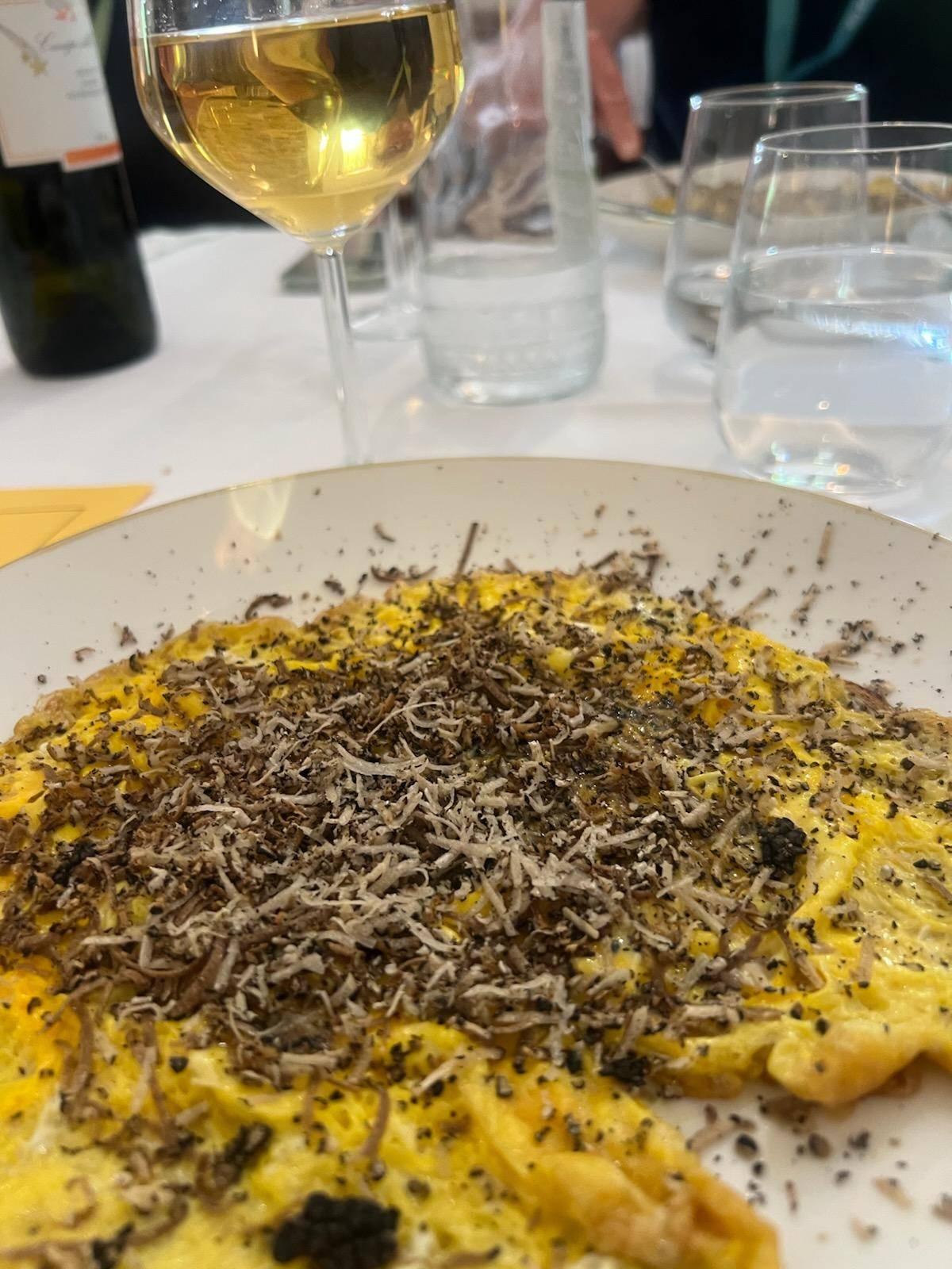 A colorful dish served on a plate with a glass of rosé wine