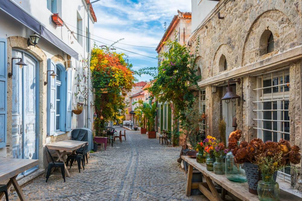 A narrow street featuring blue doors and outdoor tables