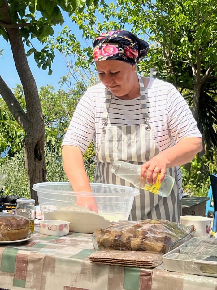 A woman in an apron prepares food on a table