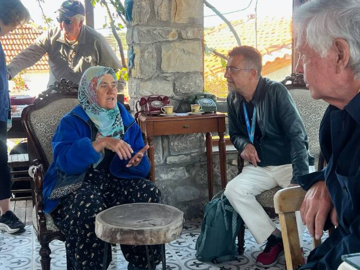 A woman talks to two men while sitting on a chair