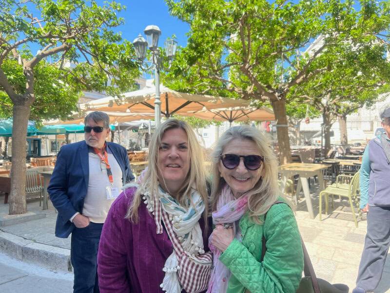 Two women pose happily for a picture in front of a cafe