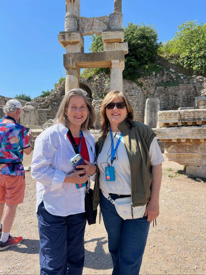 Two women pose in front of an ancient stone structure