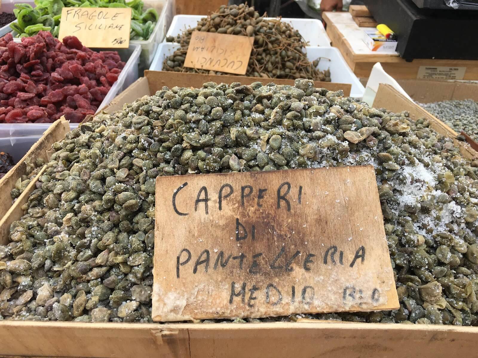 A box filled with assorted dried fruits and vegetables displayed at a vibrant market.