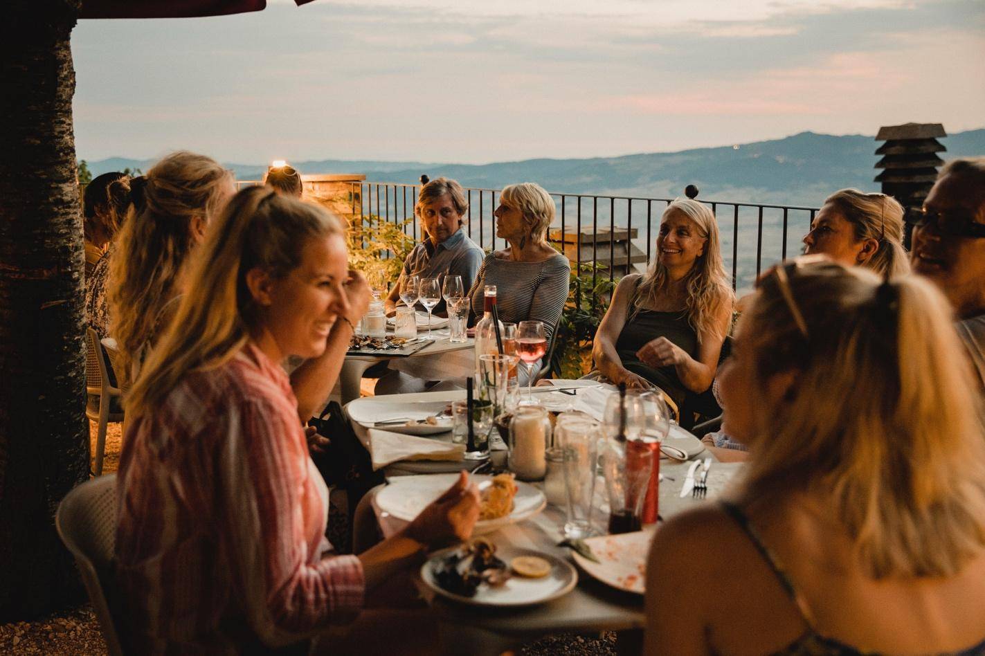 A group of people enjoying wine while seated around a table, engaged in conversation and laughter.