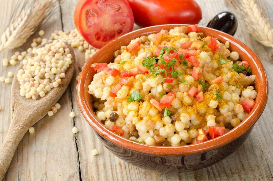 A bowl of couscous topped with diced tomatoes