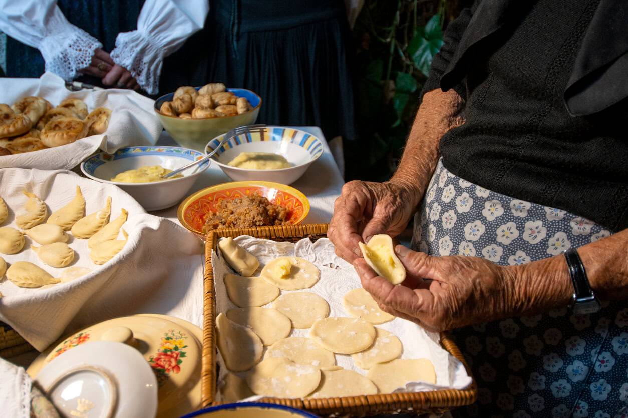 A woman is arranging food items and cooking utensils on a table while preparing a meal.