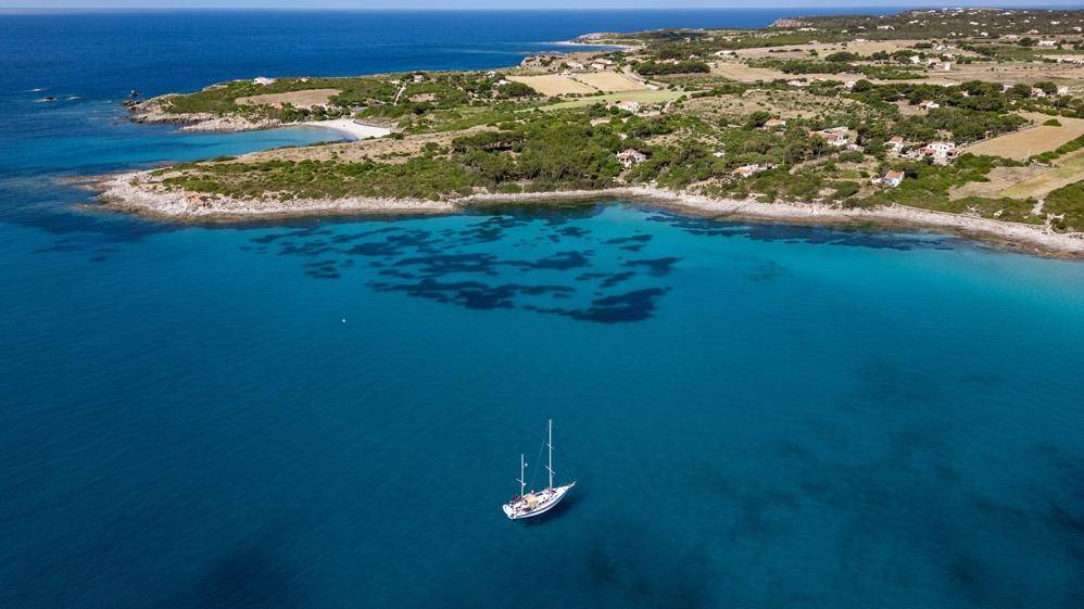 Overhead perspective of a yacht navigating the ocean, surrounded by vast blue waters and gentle waves
