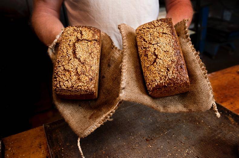 A man holds two loaves of bread