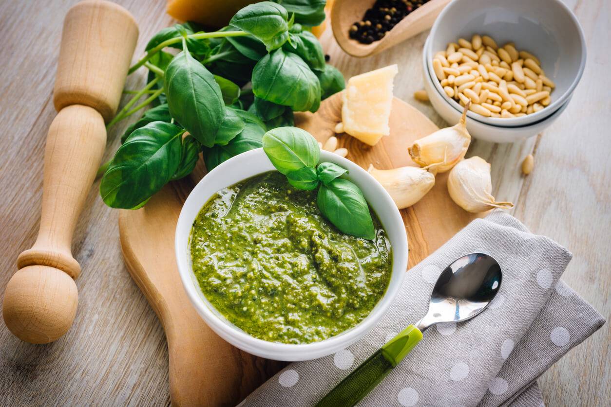 A bowl of green pesto sauce garnished with fresh basil