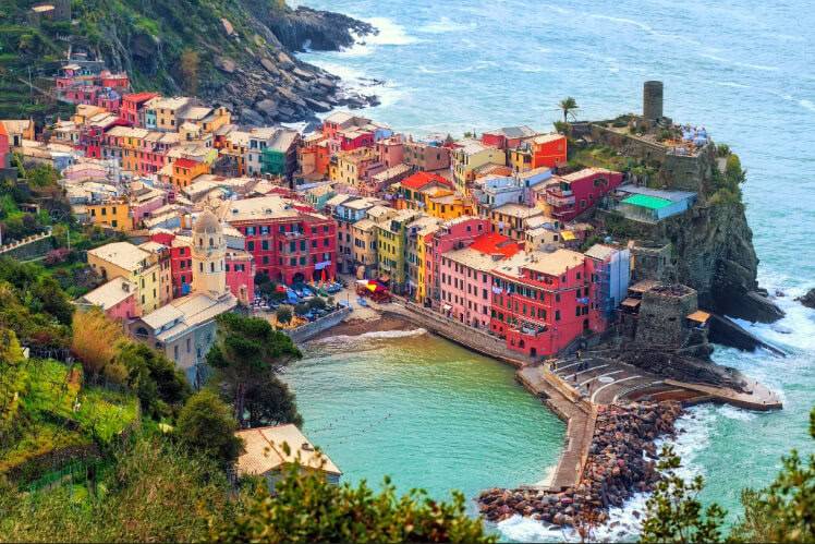 Aerial view of a vibrant coastal village with colorful houses nestled on a rocky shoreline