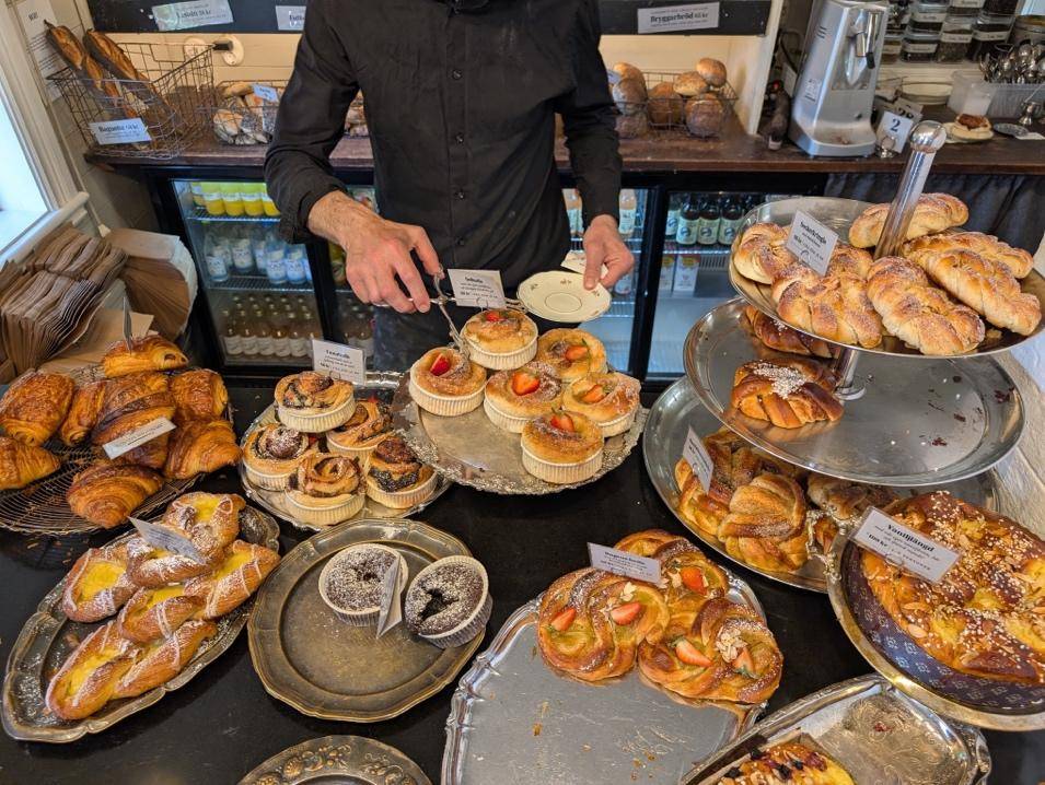 A man stands by a table filled with an assortment of delicious pastries