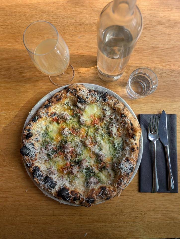 A slice of pizza on a plate next to a glass of water and a knife