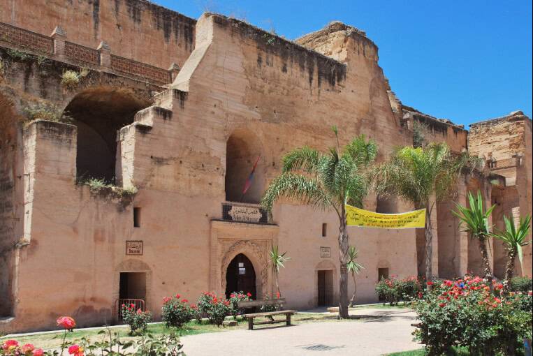 Ancient stone building with arches and palm trees