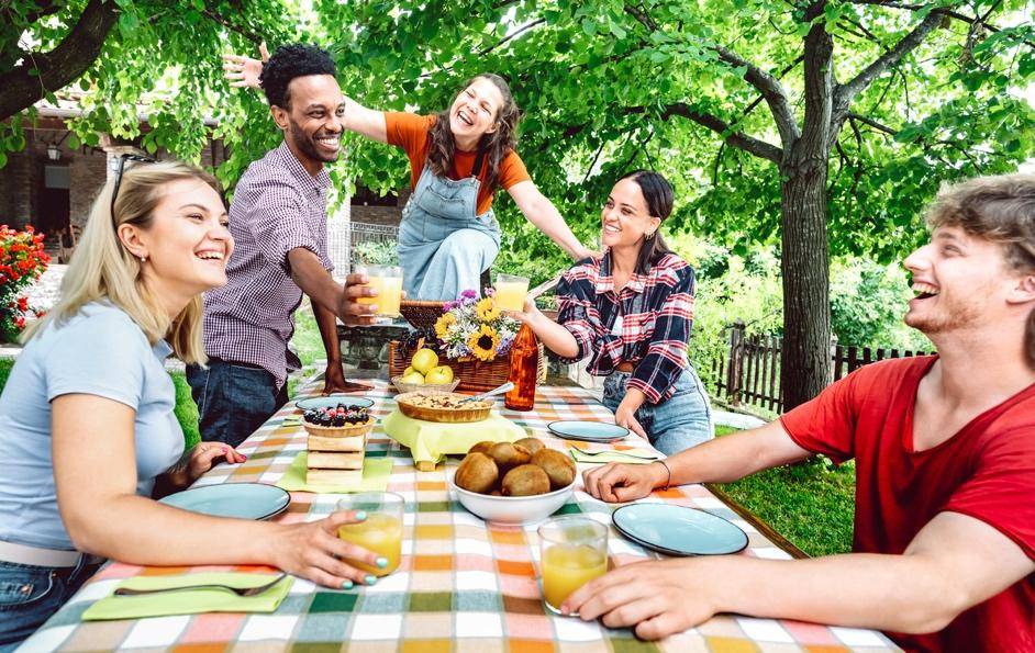 Group of friends laughing and having picnic outdoors