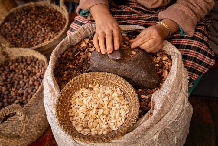 Person grinding nuts with stone in burlap sack