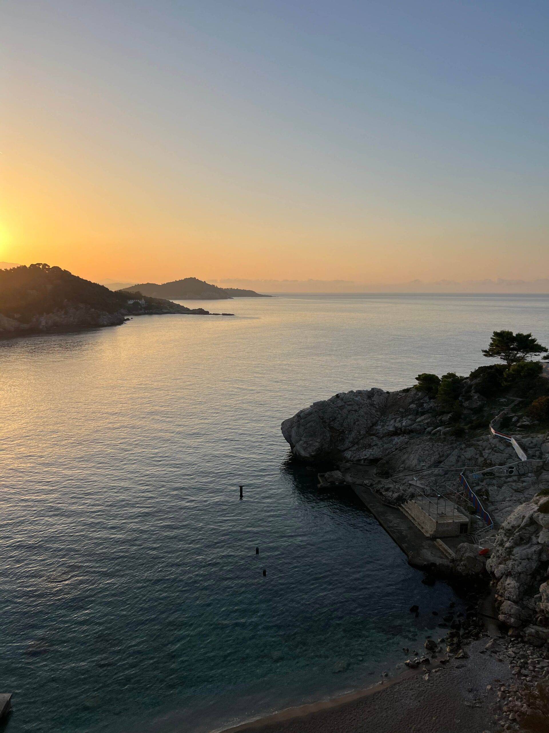 A picturesque sunset reflects on the water, showcasing the beauty of the Croatian coast